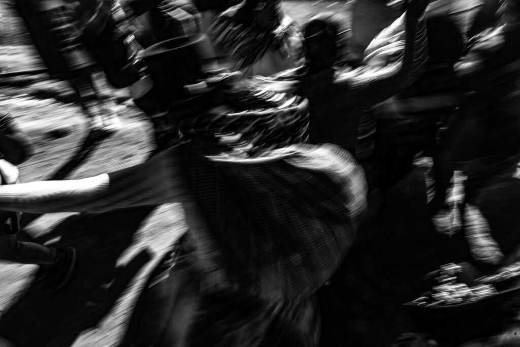 Black and white photo capturing dynamic motion in a lively street scene.